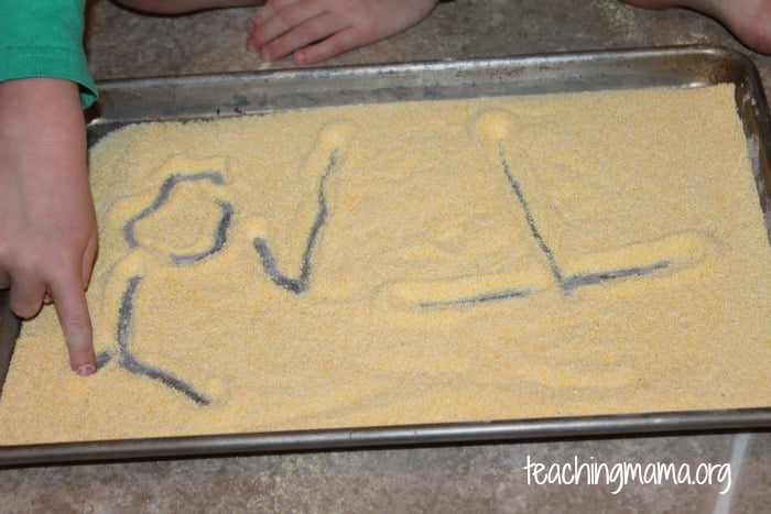 pre-writing practice on a tray with corn meal
